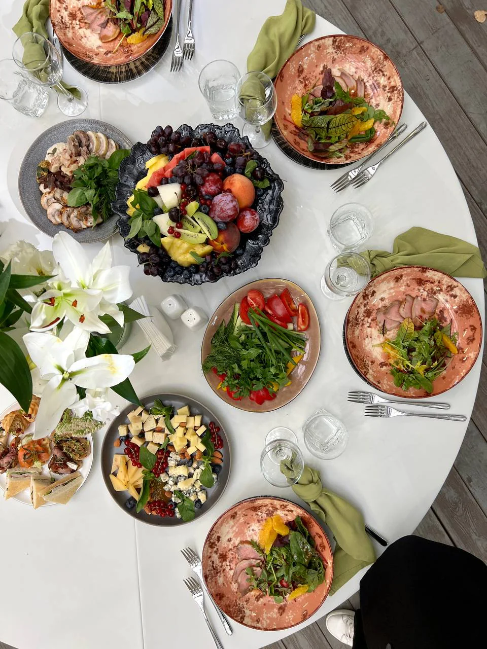 Вид сверху на стол с мясными закусками, сырами, салатами и фруктами